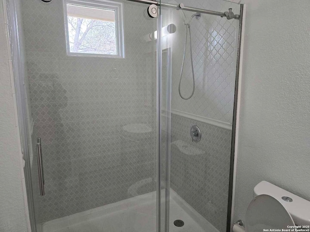 bathroom with toilet and a shower with door