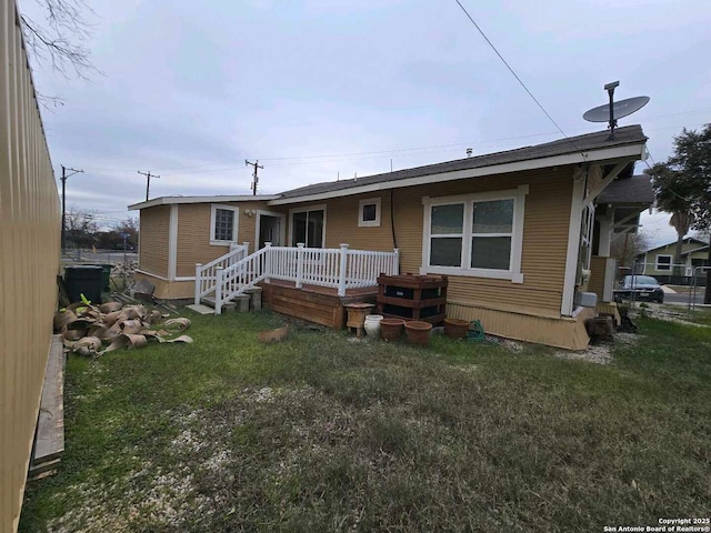 rear view of property featuring a lawn and a wooden deck