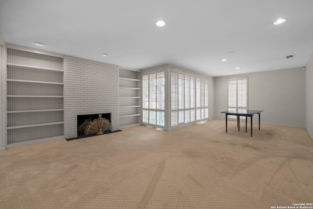 unfurnished living room featuring a brick fireplace, built in features, and light carpet