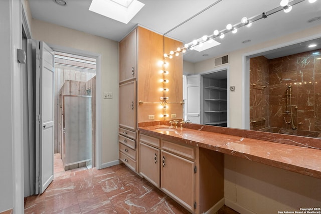 bathroom featuring a shower, a skylight, and vanity