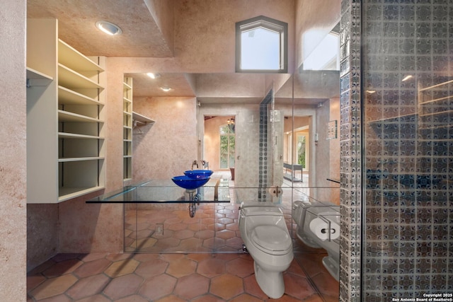 bathroom featuring toilet, tile patterned flooring, tile walls, and a wealth of natural light