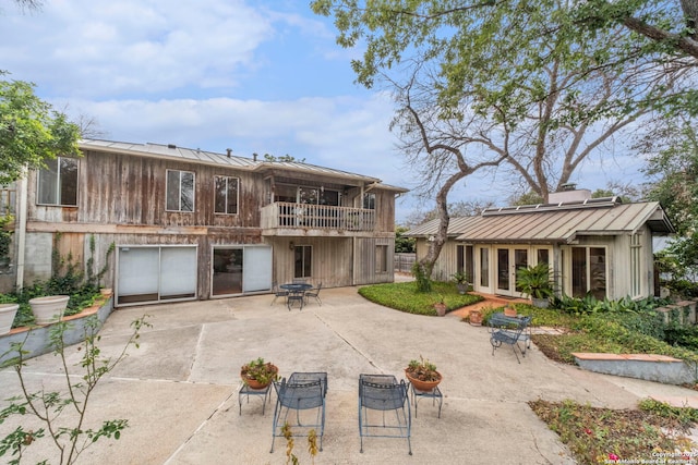 rear view of house with a balcony, a patio, and a garage