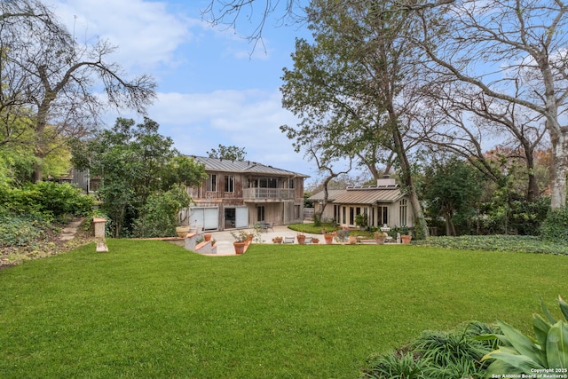 rear view of property with a balcony, a patio area, and a yard