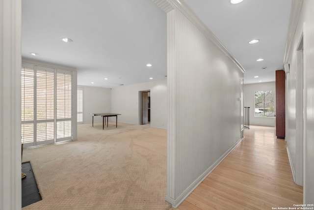 corridor with ornamental molding and light carpet