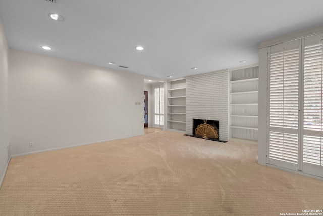 unfurnished living room with a brick fireplace, built in shelves, and light carpet