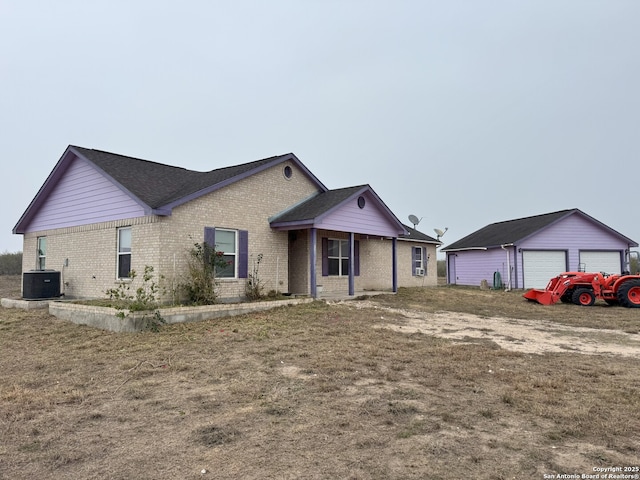 ranch-style house with central AC unit, a front lawn, a garage, and an outdoor structure