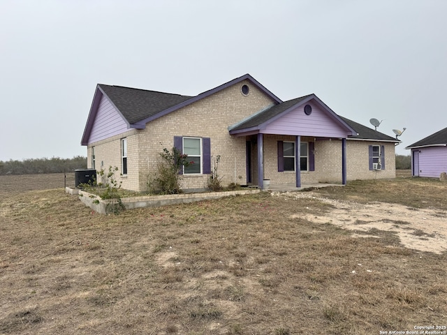 single story home with cooling unit and a front yard