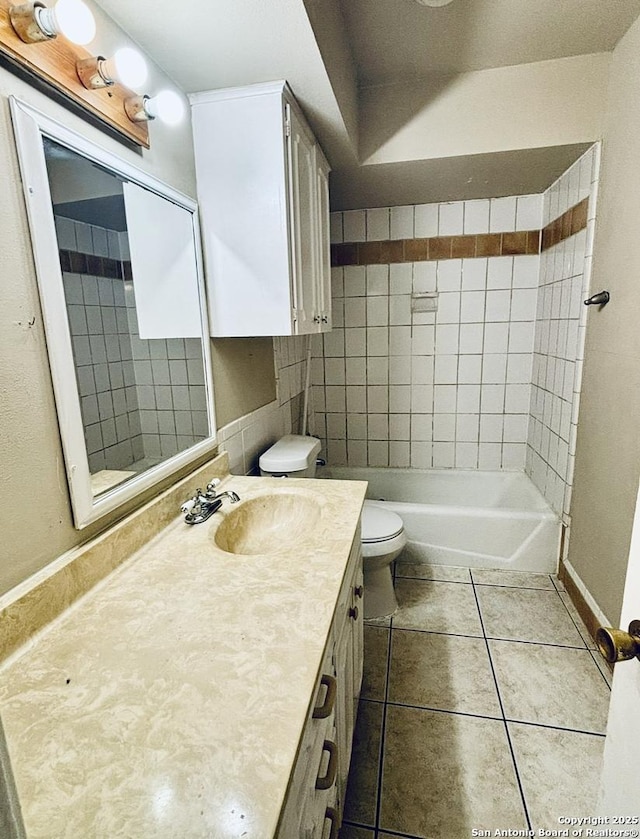 full bathroom with toilet, tiled shower / bath, tile patterned floors, and vanity