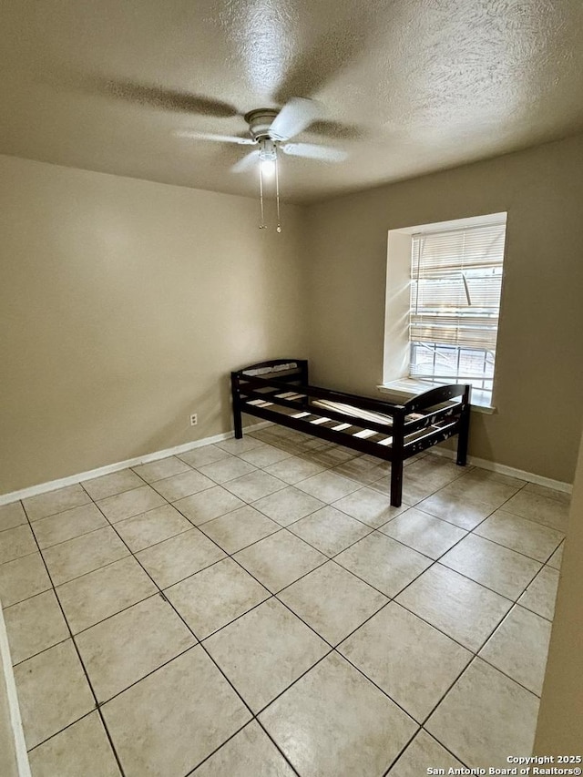 unfurnished bedroom with a textured ceiling, light tile patterned flooring, and ceiling fan