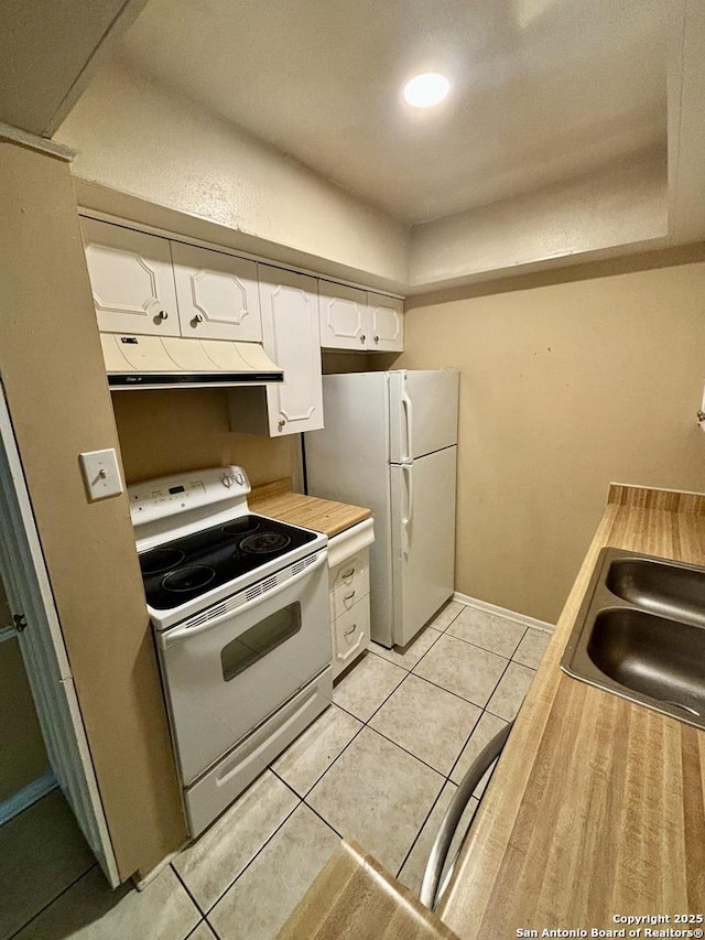 kitchen featuring white appliances, light tile patterned floors, white cabinets, extractor fan, and sink