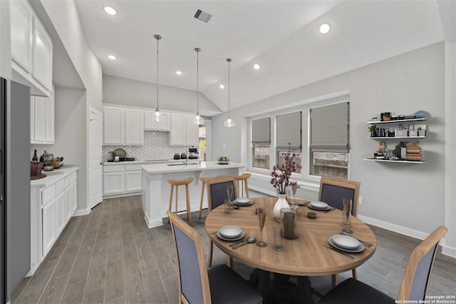 dining area featuring sink, a wealth of natural light, hardwood / wood-style floors, and lofted ceiling