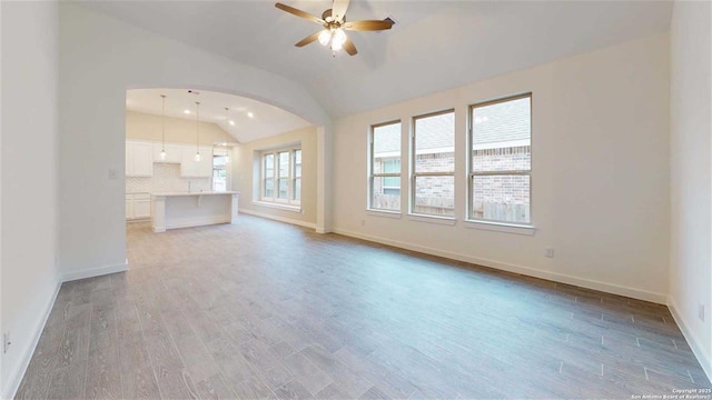 unfurnished living room featuring ceiling fan, vaulted ceiling, and light hardwood / wood-style flooring