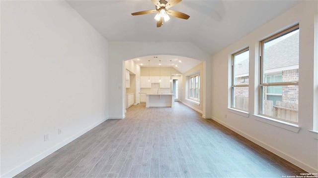 unfurnished living room with ceiling fan, lofted ceiling, and wood-type flooring