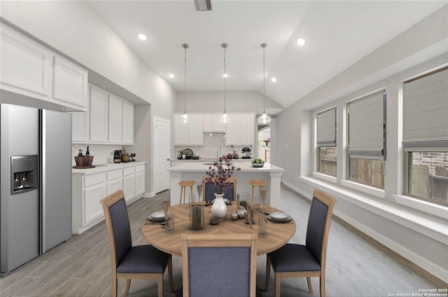 dining room featuring light wood-type flooring and vaulted ceiling