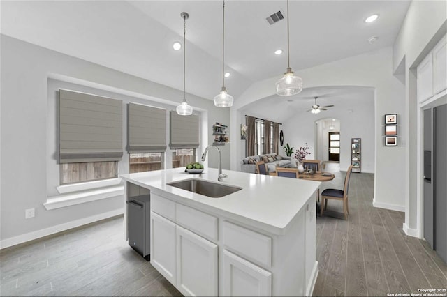 kitchen featuring decorative light fixtures, white cabinets, a center island with sink, and sink