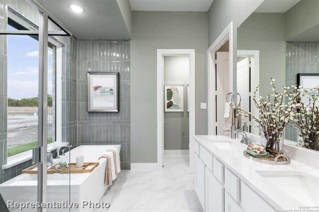 bathroom with vanity, tile walls, plenty of natural light, and a bath