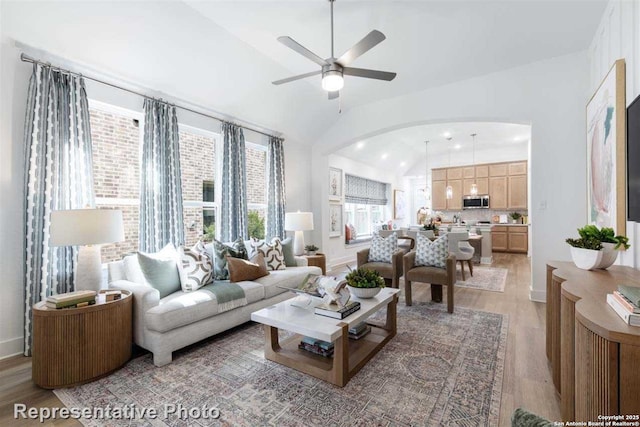 living room with light hardwood / wood-style floors, ceiling fan, and vaulted ceiling