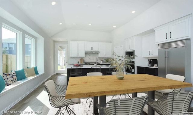 kitchen with hardwood / wood-style flooring, stainless steel appliances, tasteful backsplash, and white cabinetry