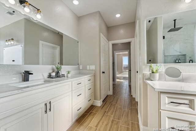 bathroom with tiled shower and vanity