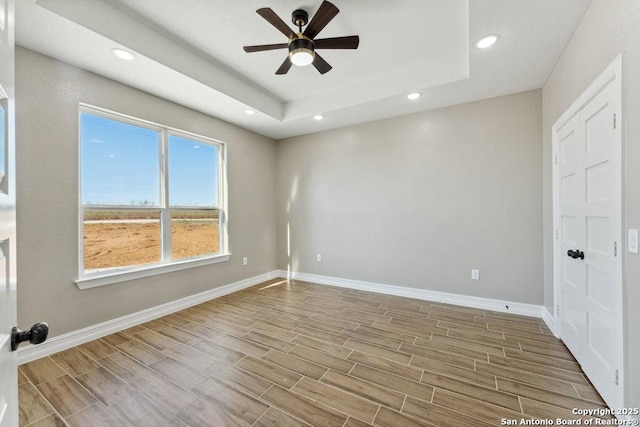 unfurnished room featuring a raised ceiling and ceiling fan