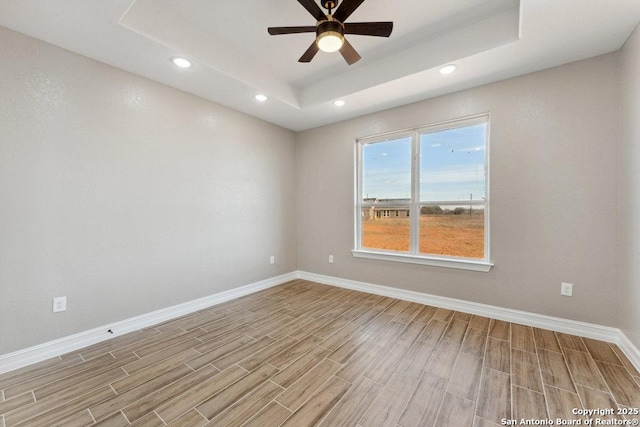 spare room with a raised ceiling and ceiling fan