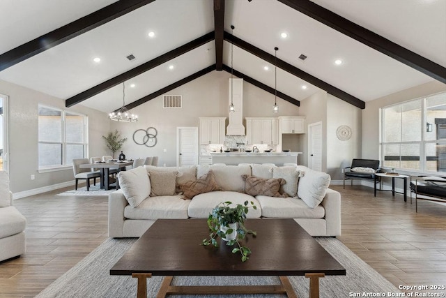 living room with an inviting chandelier, high vaulted ceiling, and beamed ceiling