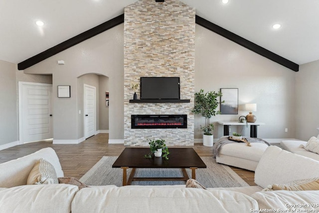 living room with high vaulted ceiling, beam ceiling, light hardwood / wood-style floors, and a stone fireplace