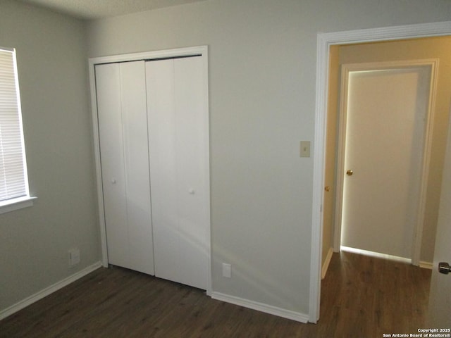 unfurnished bedroom with a closet and dark hardwood / wood-style floors