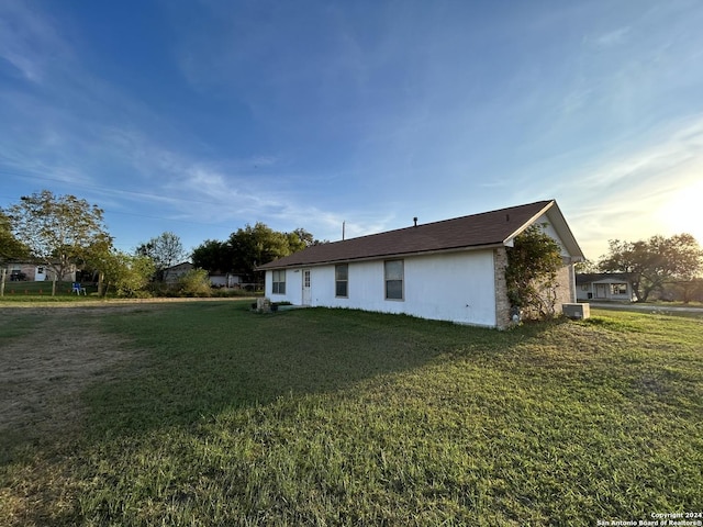 view of side of home with a yard and central AC