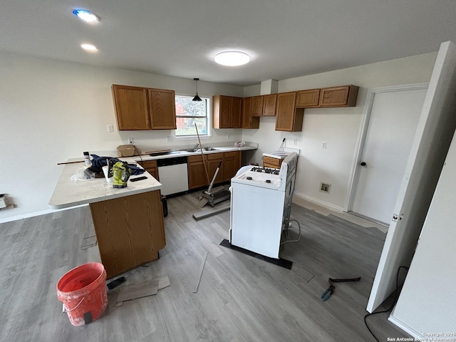 kitchen featuring sink, washer / clothes dryer, light wood-type flooring, stainless steel dishwasher, and pendant lighting