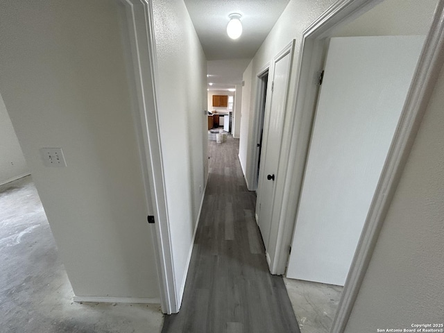 hall with a textured ceiling and wood-type flooring