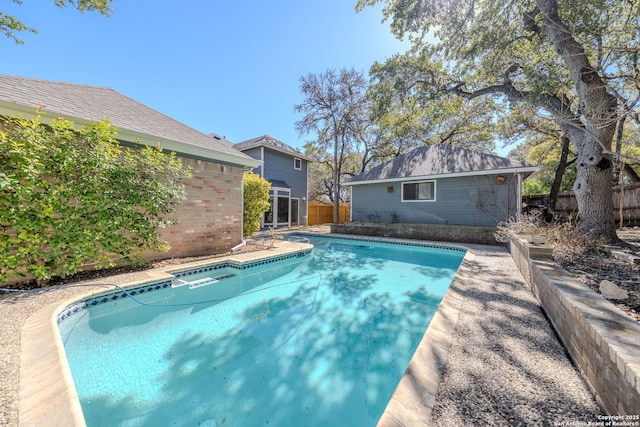 view of swimming pool with fence, a fenced in pool, and an outbuilding