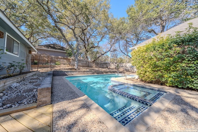 view of swimming pool featuring a pool with connected hot tub, a fenced backyard, and a patio