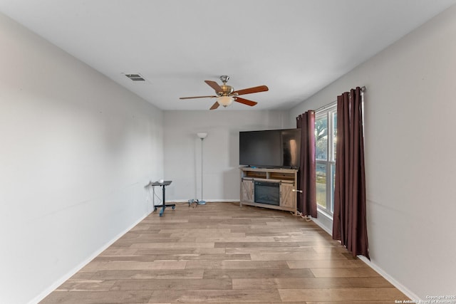 unfurnished living room featuring ceiling fan, light wood-type flooring, and a fireplace