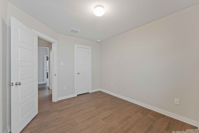 unfurnished bedroom featuring a closet, wood-type flooring, and a textured ceiling