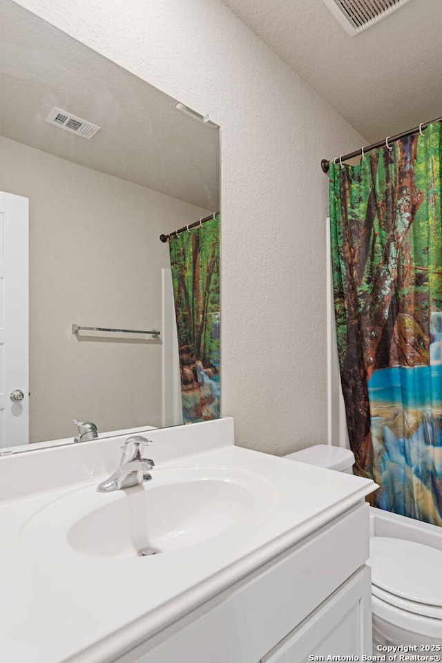 bathroom with toilet, vanity, and curtained shower