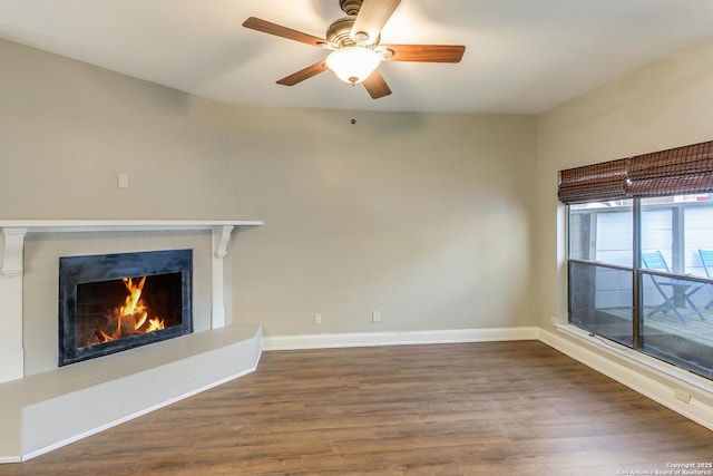 unfurnished living room featuring a tiled fireplace, hardwood / wood-style floors, and ceiling fan