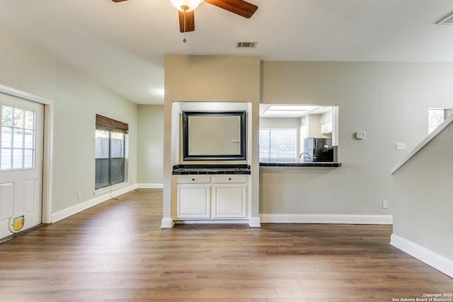 unfurnished living room featuring ceiling fan, plenty of natural light, and dark hardwood / wood-style floors