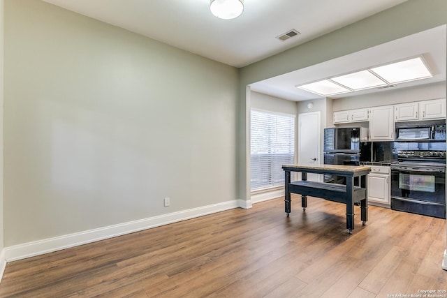 kitchen featuring light hardwood / wood-style floors, decorative backsplash, white cabinetry, and black appliances