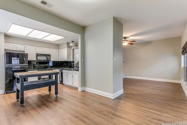 kitchen featuring light hardwood / wood-style flooring, black appliances, tasteful backsplash, white cabinetry, and ceiling fan