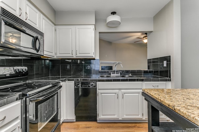 kitchen featuring black appliances, tasteful backsplash, white cabinetry, and sink