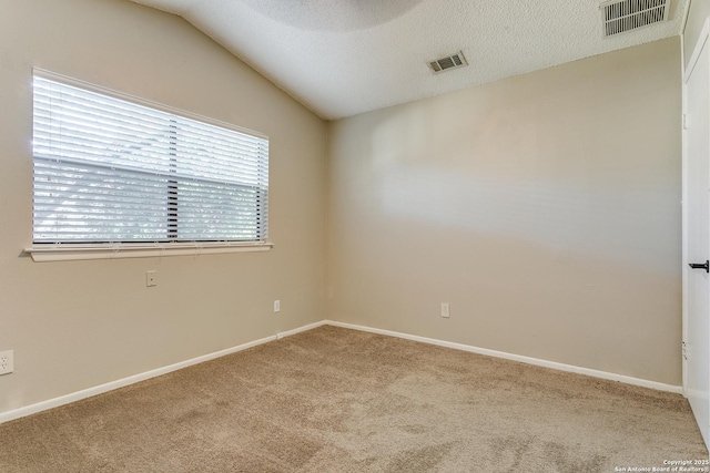 carpeted spare room with a textured ceiling and vaulted ceiling