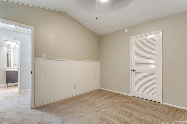 carpeted empty room with lofted ceiling, a textured ceiling, and ceiling fan