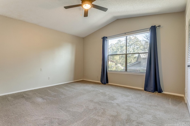 carpeted empty room featuring a textured ceiling, ceiling fan, and vaulted ceiling