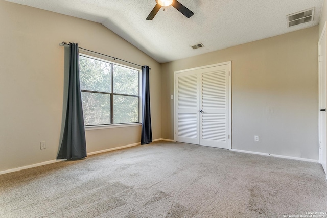 unfurnished bedroom with vaulted ceiling, carpet, a closet, ceiling fan, and a textured ceiling