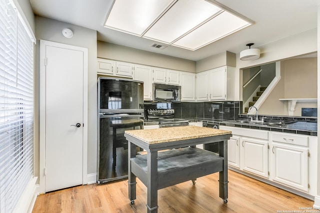 kitchen with backsplash, white cabinets, black appliances, and sink