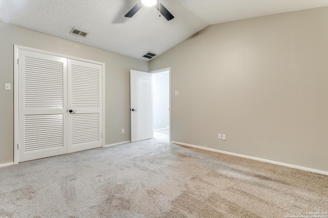 unfurnished bedroom featuring a closet, ceiling fan, vaulted ceiling, and carpet floors