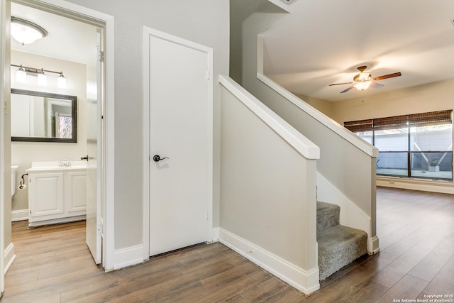 staircase with wood-type flooring and ceiling fan