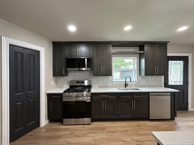 kitchen with appliances with stainless steel finishes, light hardwood / wood-style floors, tasteful backsplash, and sink