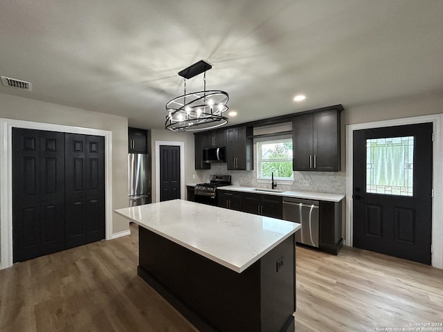 kitchen with pendant lighting, a center island, a notable chandelier, backsplash, and appliances with stainless steel finishes